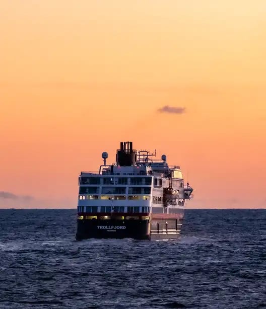 Ms Trollfjord seiler inn i soldnedgang.