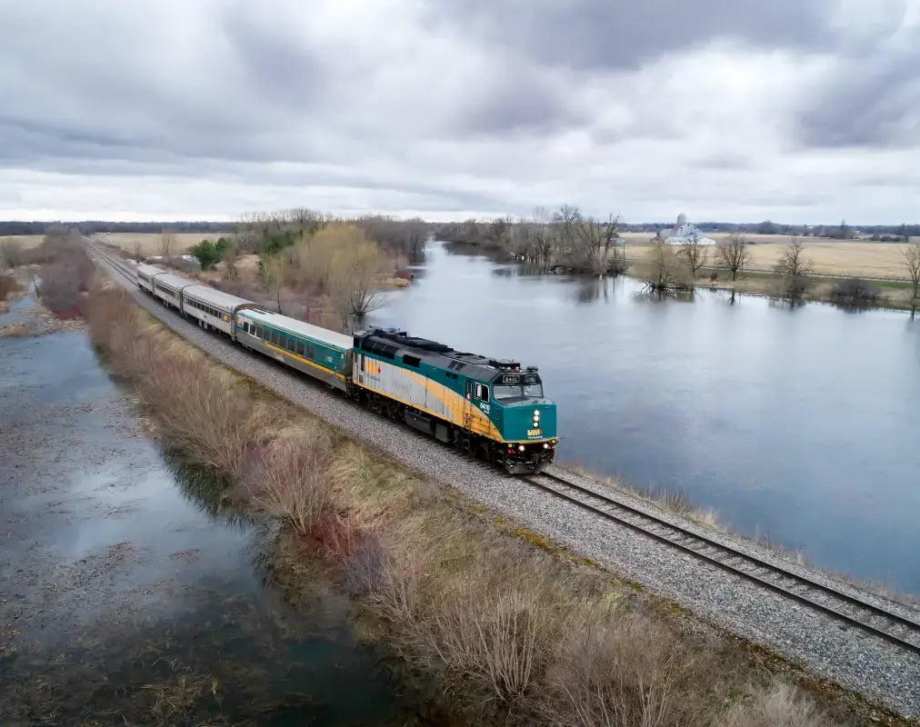 Et Via Rail tog som kjører på en opphøyning med vann på hver side.