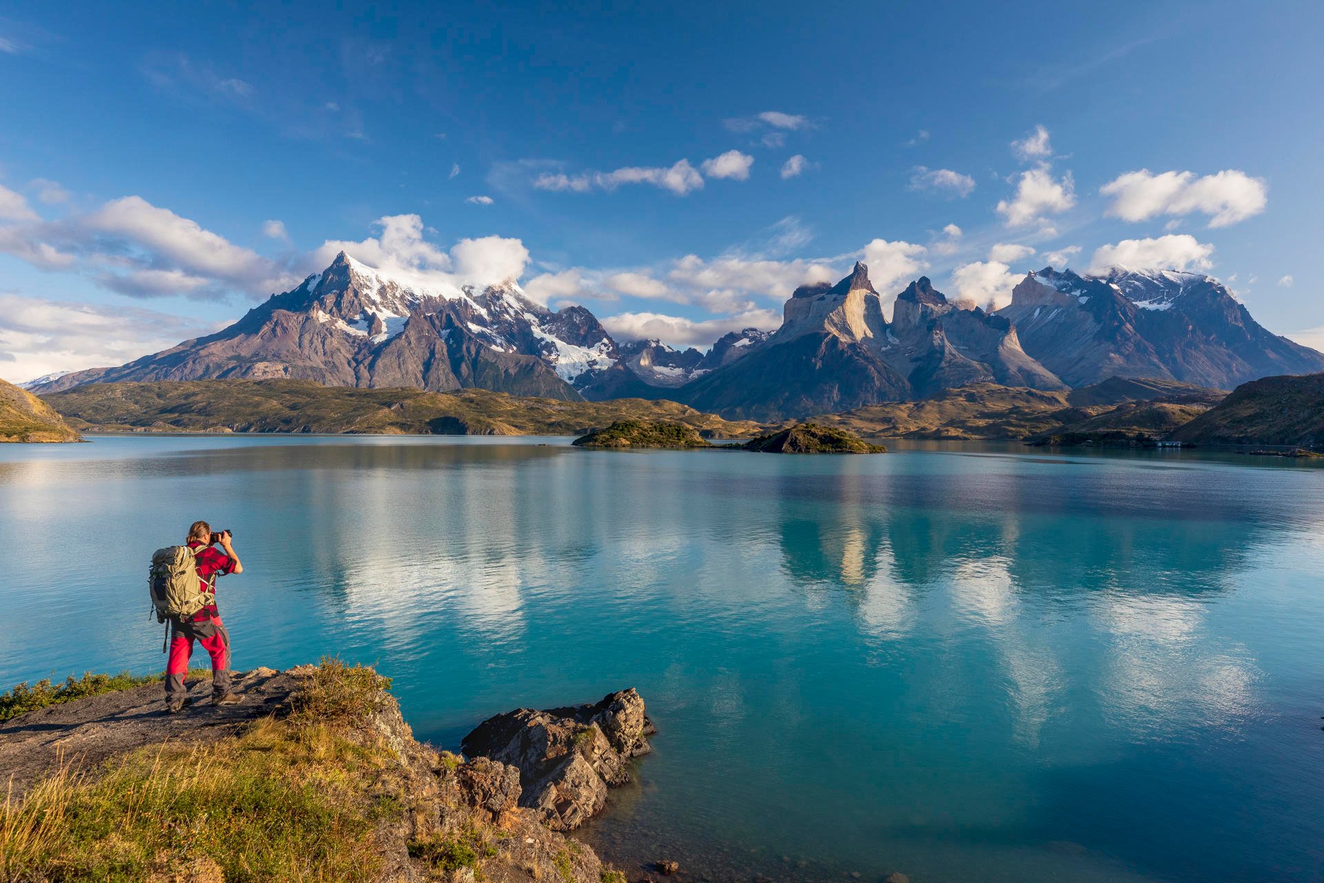 Turist som nyter utsikt over en innsjø med fjellene Torres de paine i det fjerne. Turist som nyter utsikt over en innsjø med fjellene Torres de paine i det fjerne.
