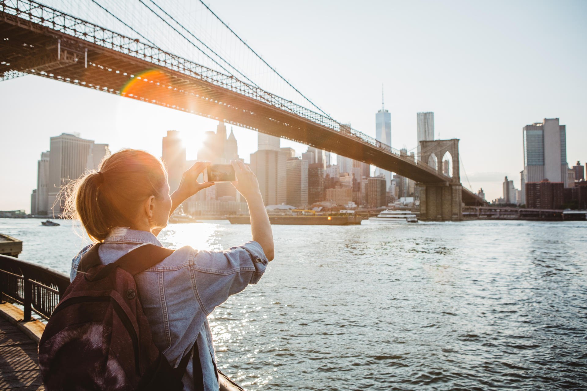 En kvinnelig turist tare bilde av Manhatten fra DUNBO-siden.