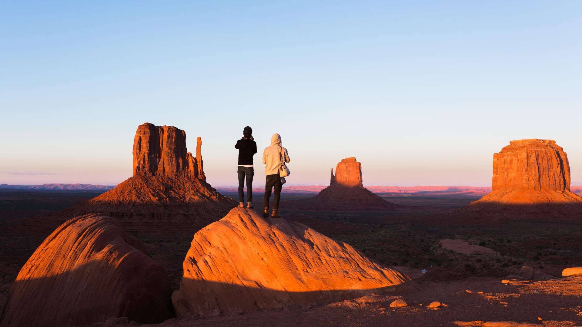 Solnedgang i Monument Valley. To personer nyter utsikten Solnedgang i Monument Valley. To personer nyter utsikten