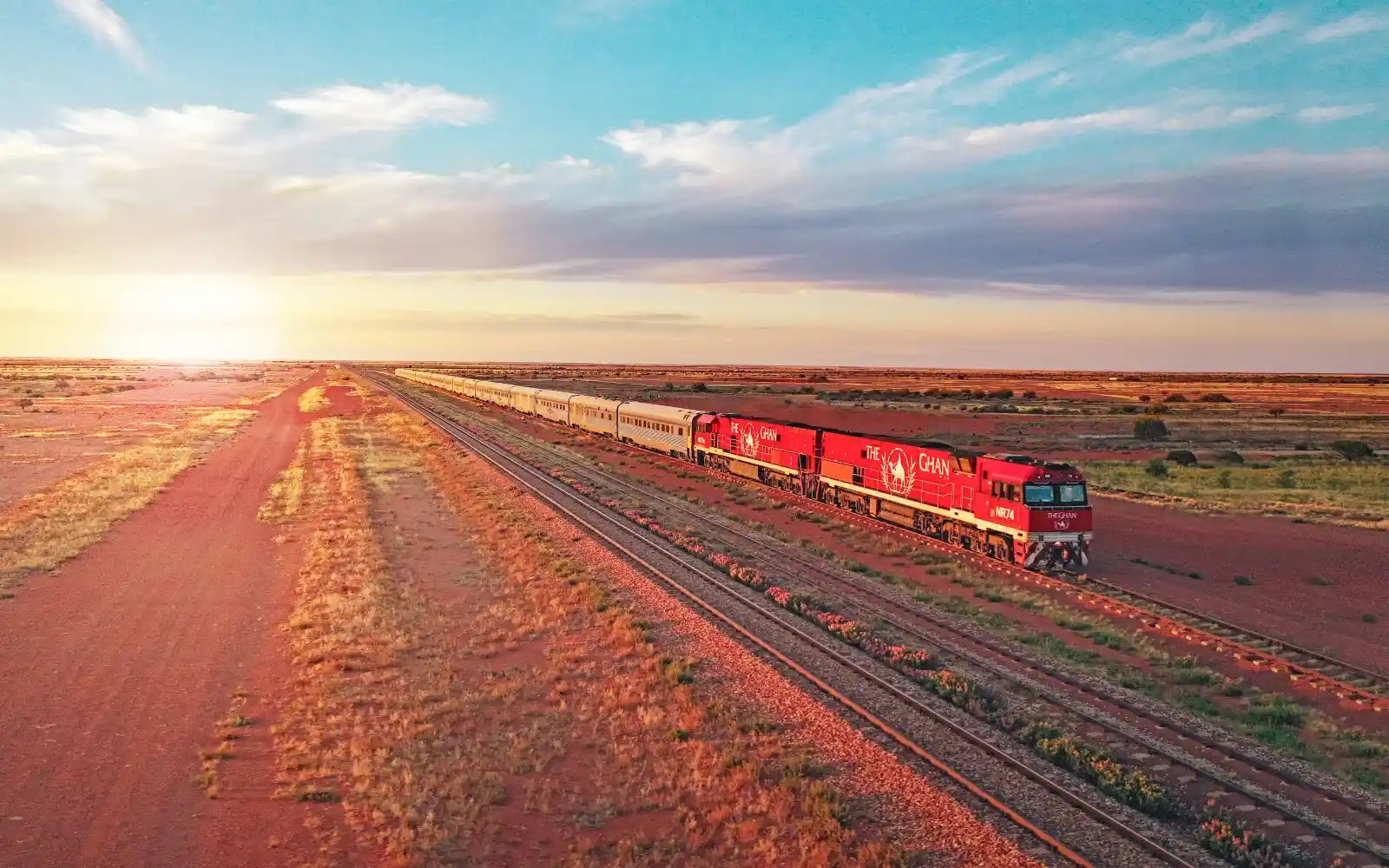 Toget The Ghan med to lokomotiv og passasjervogner i solnedgang.