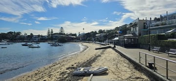 En bukt med småbåter, sandstrand og promende med restauranter