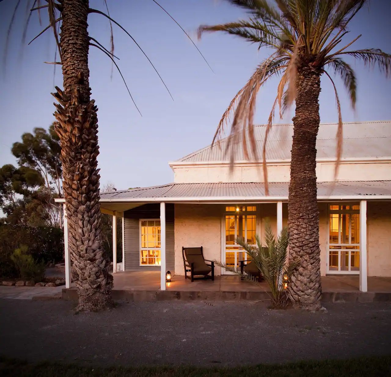 Verandaen på Arkaba Homestead med lys i vinduene i kveldslys.