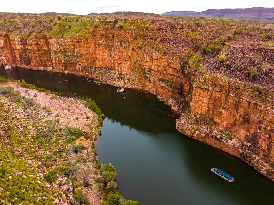 Båt på elven mellom høye røde klipper i Chamberlain Gorge.