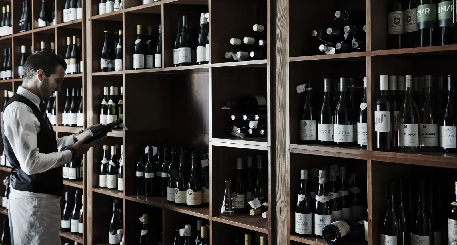 Sommelier ved vinhyllene i vinkjelleren.