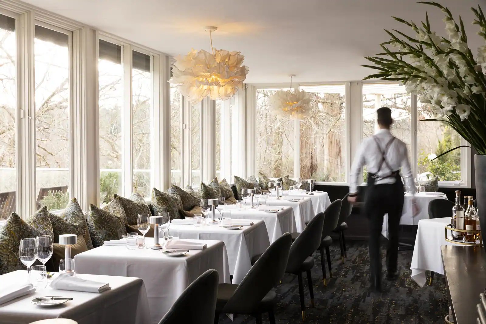 Restauranten med dekkede bord og servitør.