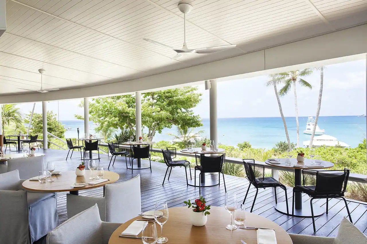 Restaurantterrassen med bord og utsikt mot havet.