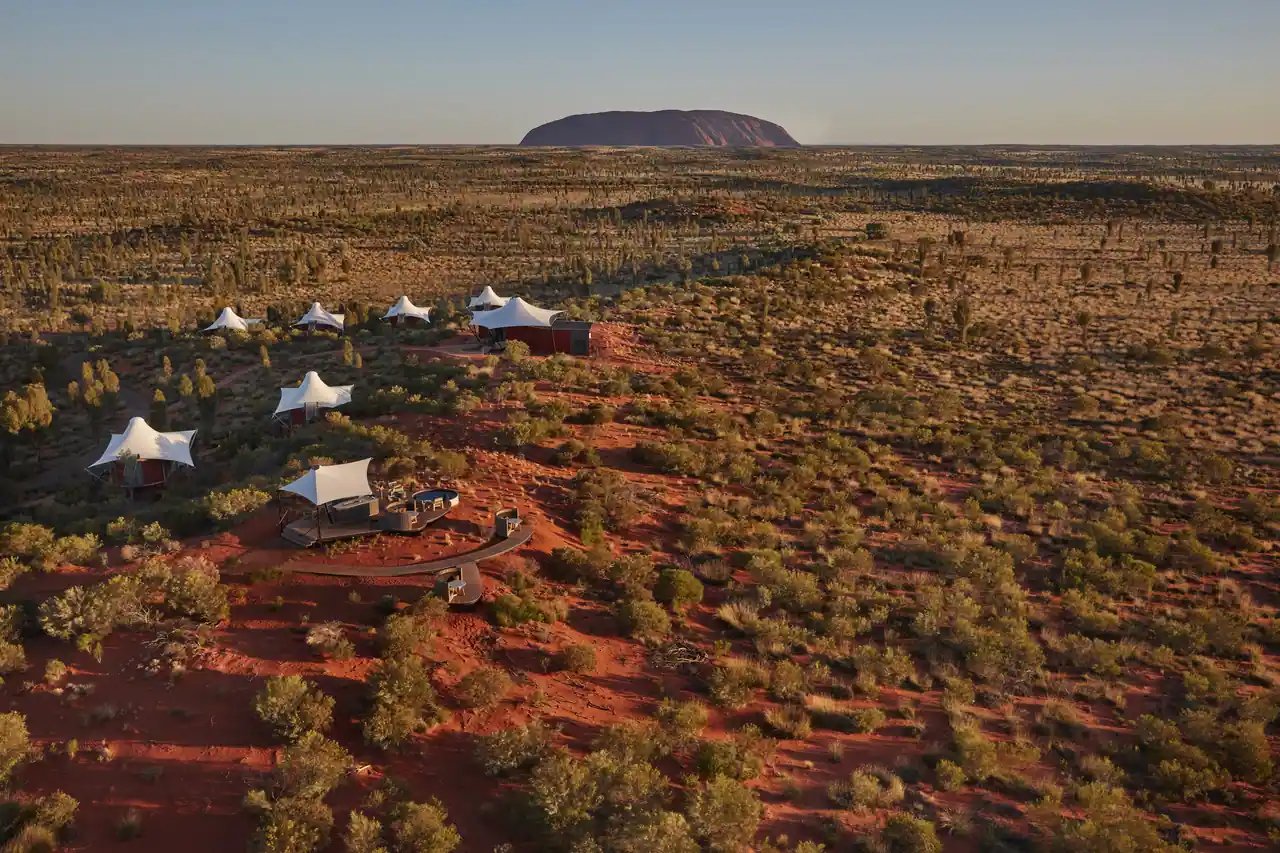 Uluru i horisonten og lodgens telt i det røde landskapet