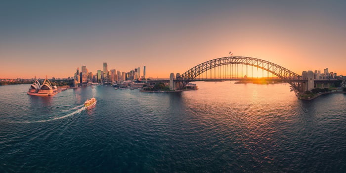 Solnedgang over sydney by. Operahuset, bruen og en ferje seiler inn mot Circular Quay