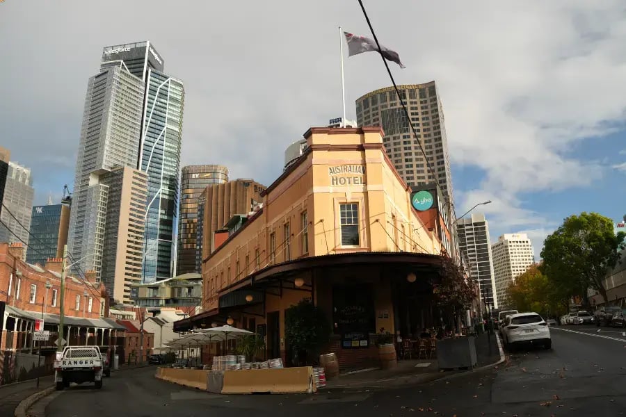 a street view with a prominent building in the foreground labeled 'Ashburton Hotel'. There are cars parked on the side of the road, and high-rise buildings can be seen in the background, indicating an urban setting.