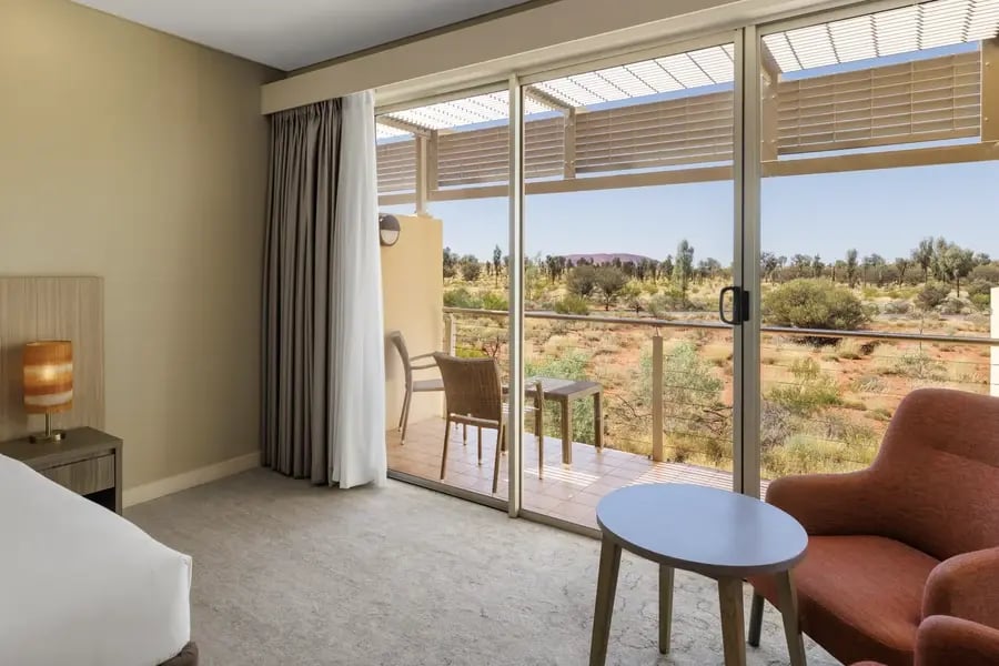 Hotellrom med skyvedører ut til balkong og ørkenlandskap.
