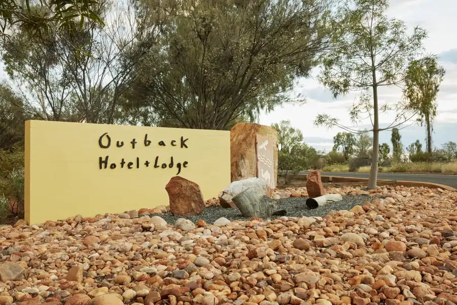 Skilt for Outback Hotel and Lodge omgitt av røde steiner.