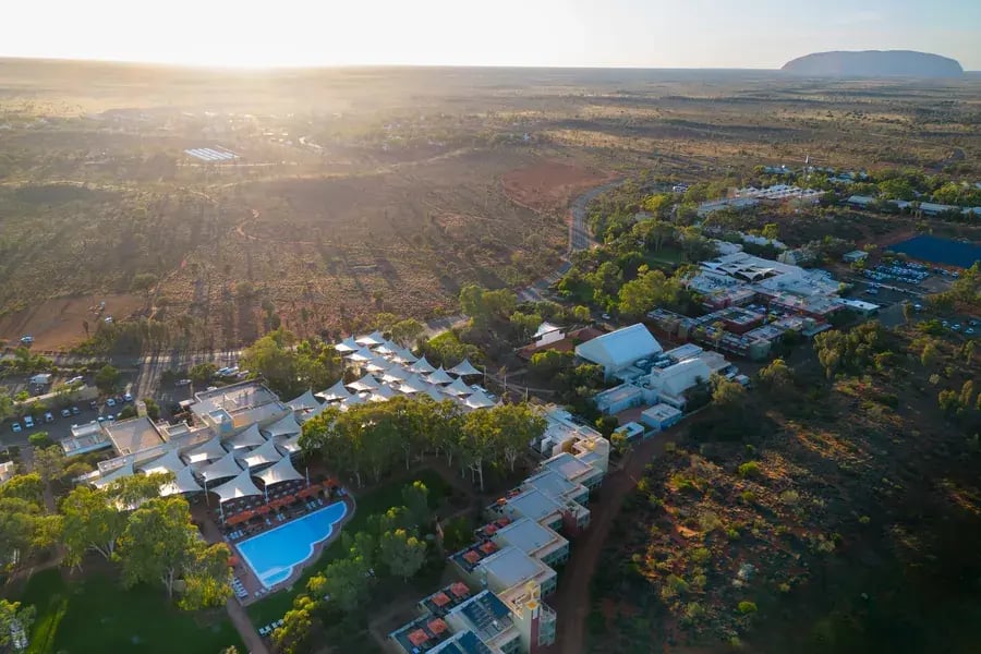 Flyfoto av resortet i solnedgang med Uluru i bakgrunnen.