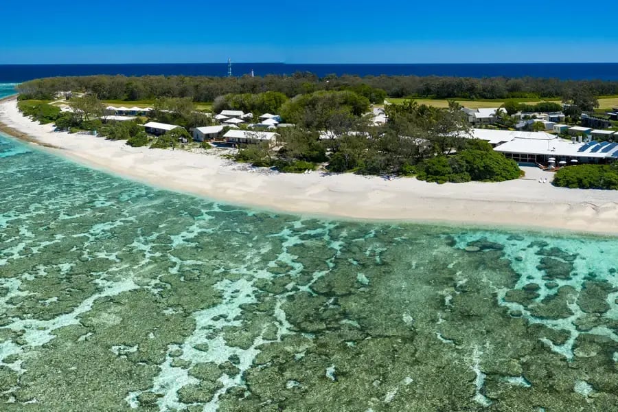 Flyfoto av resortet og hvit strand langs revet.