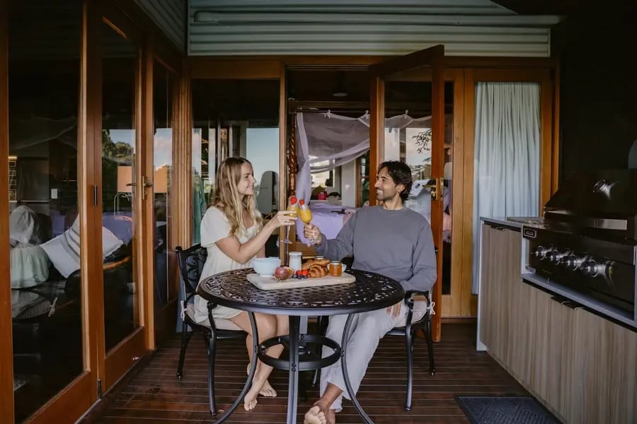 Par skåler med frokost ved et bord innenfor glassdørene på terrassen.