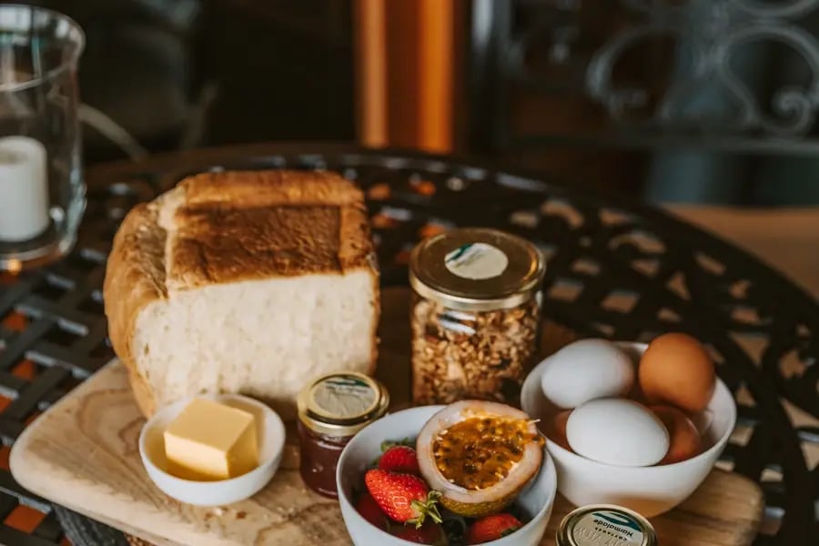 Frokostbrett med brød, egg, jordbær og syltetøy på et smijernsbord.
