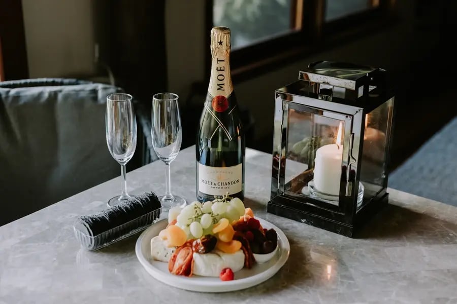 Champagne, glass og fruktfat på et bord med lykt.