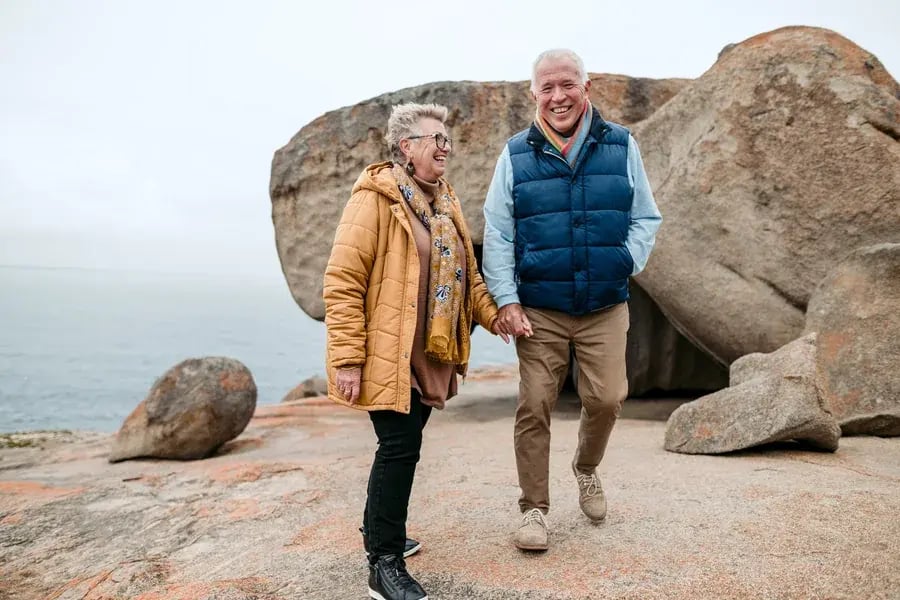 Eldre par som går hånd i hånd blant de store granittblokkene ved Remarkable Rocks.