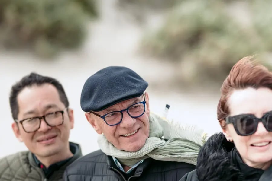 Tre gjester med smil og varme jakker i sanddynene ved Seal Bay.