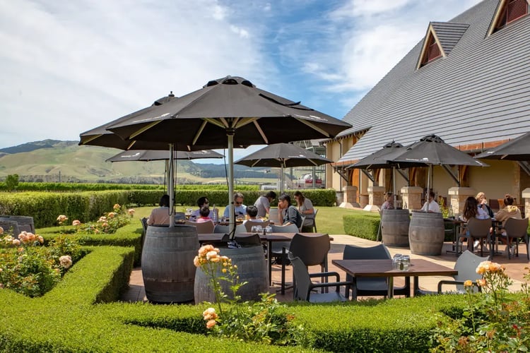 utendørs restaurant område på en restaurant. Vintønner, bord, stoler og mennesker som koser seg.