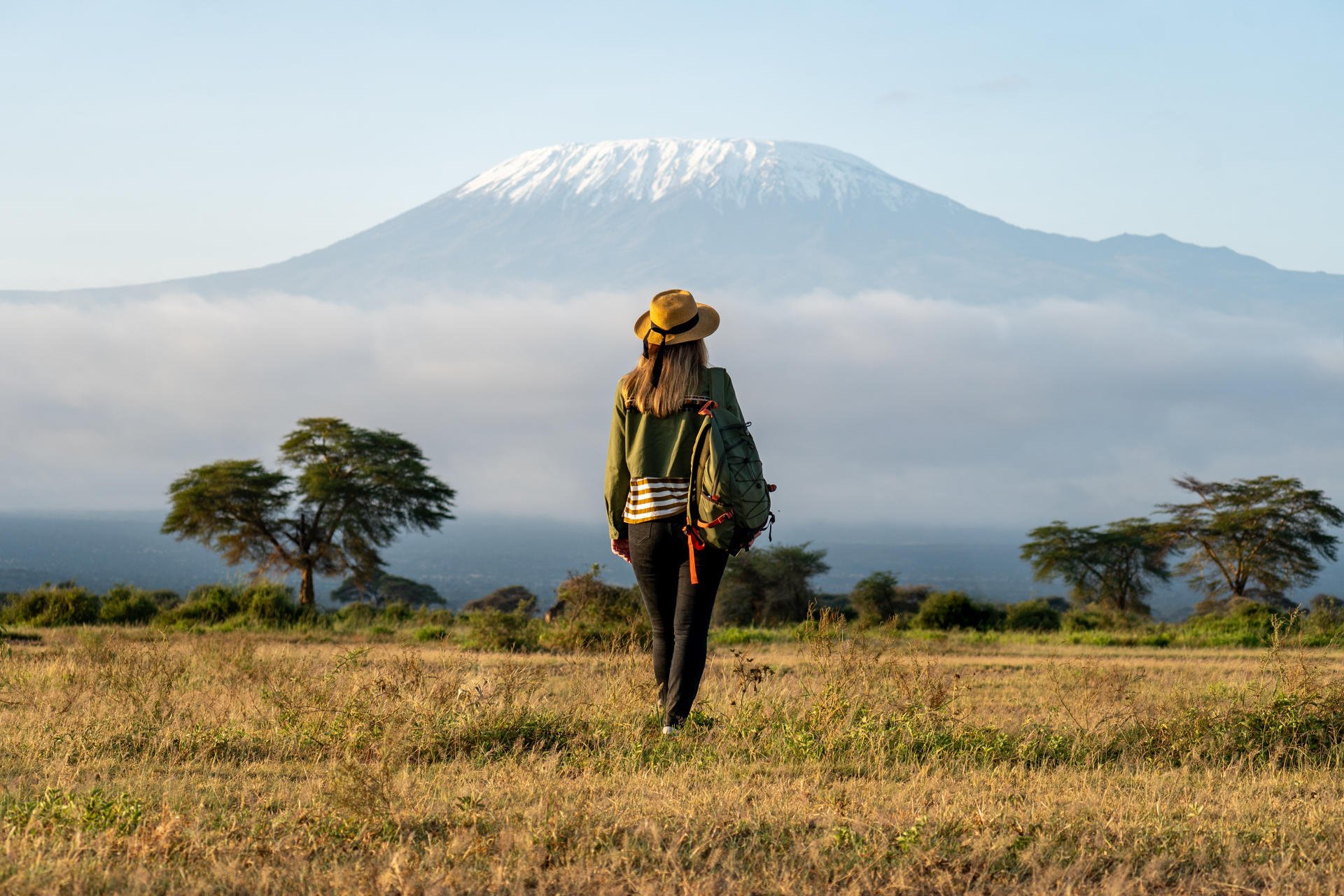 En safariturist som nyter utsikten mot Kilimanjaro. Man ser den snødekte toppen.