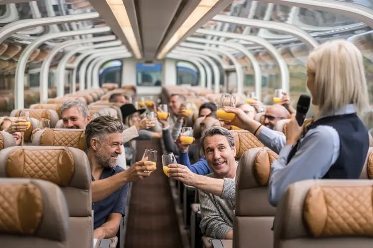 A group of people are seated in rows on a bus, each holding a glass of orange juice, seemingly participating in a social event or celebration.