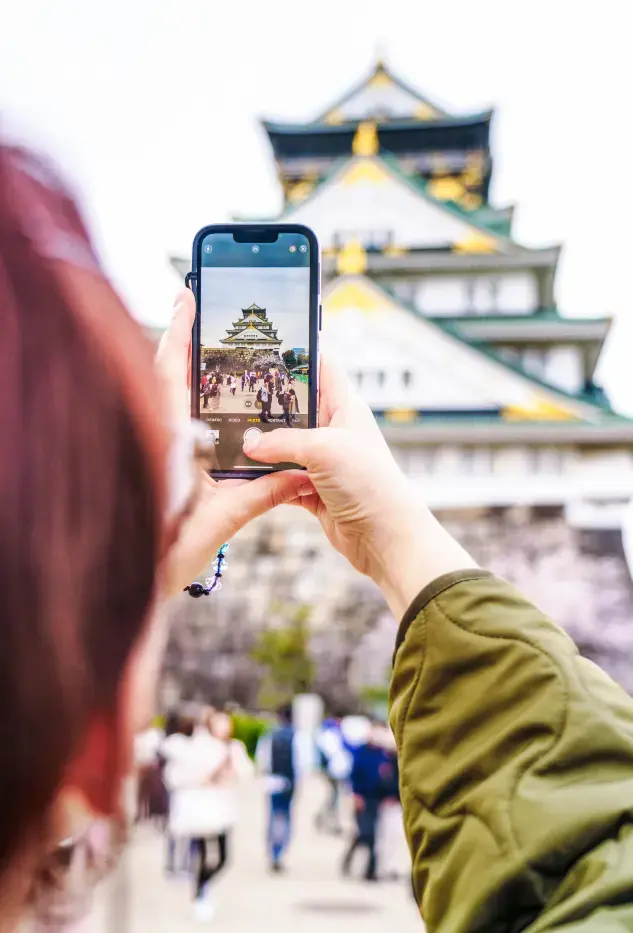 Man ser gjennom en mobilskjer hvor en turist tar bilde av et tempel. Man ser gjennom en mobilskjer hvor en turist tar bilde av et tempel.
