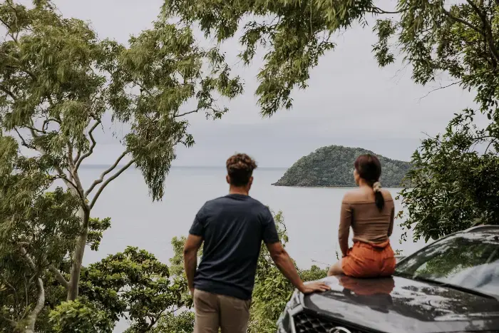 Et par som sitter på panseret på en bil og ser utover horisonten og havet. Et par som sitter på panseret på en bil og ser utover horisonten og havet.
