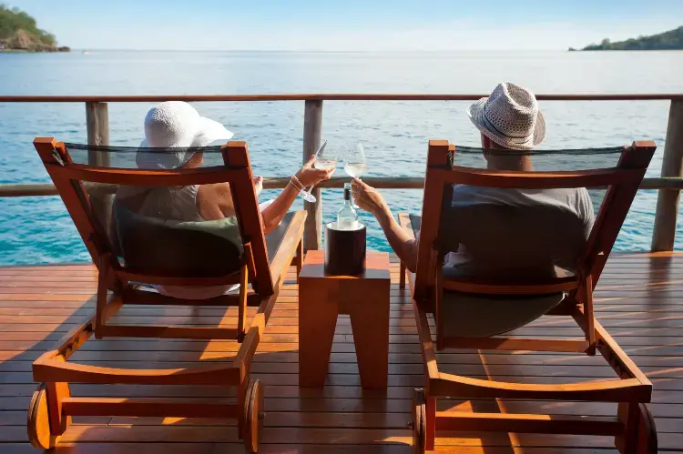 Et par sitter i solsenger med et glass vin og nyter utsikten over havet Et par sitter i solsenger med et glass vin og nyter utsikten over havet