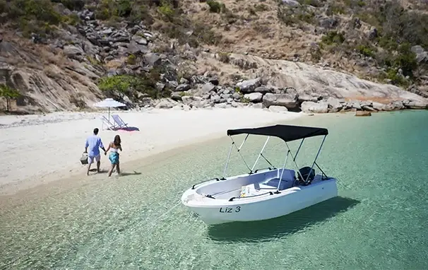 Båt på Lizard Island, ved en strand hvor et par går hånd i hånd