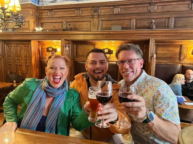 En dame og to menn, tar en skål i en bar