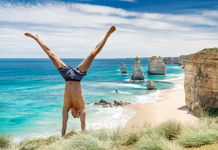 En mann som står på hender ved Twelve Apostles. En mann som står på hender ved Twelve Apostles.